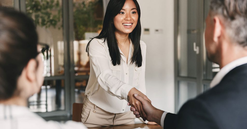 Woman shaking hands with another persoo across a desk